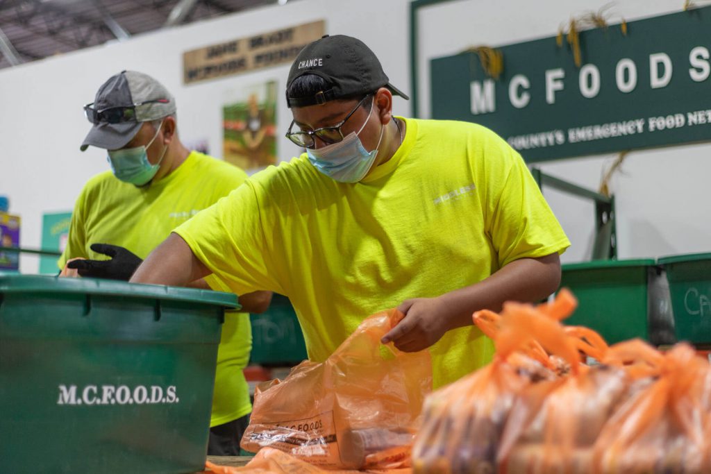 A volunteer works at MCFOODS, a local food pantry, to package meals for those in need.